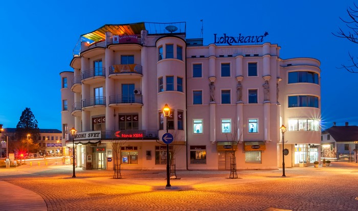 Building with "Lokakava" sign and street lights at dusk