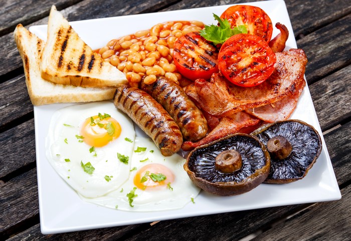 Full English breakfast with sausages, bacon, eggs, beans, mushrooms, and toast