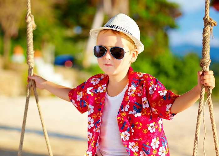 Boy in Hawaiian shirt and hat on a swing