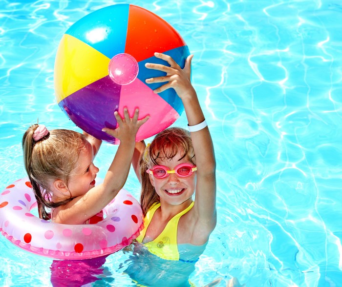 Two little girls playing with a beach ball in a pool