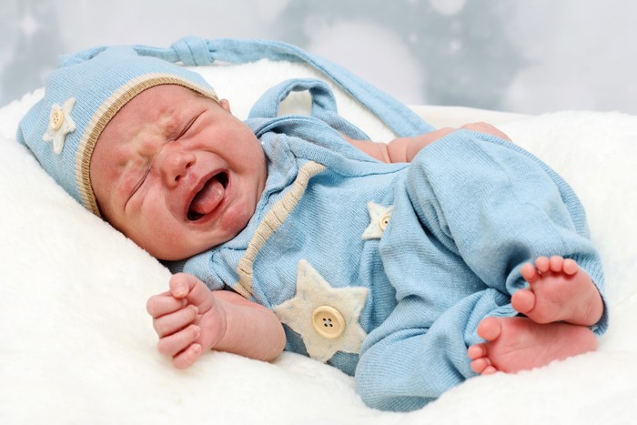 Crying baby in blue winter hat and outfit