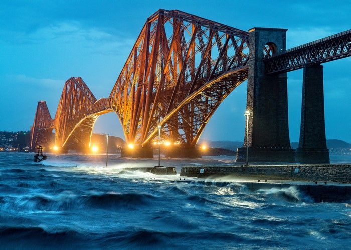 Forth Bridge at night with stormy waves