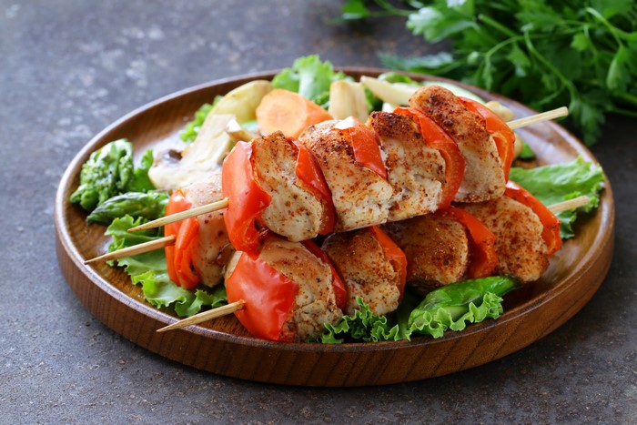 Chicken and vegetable skewers on a wooden plate