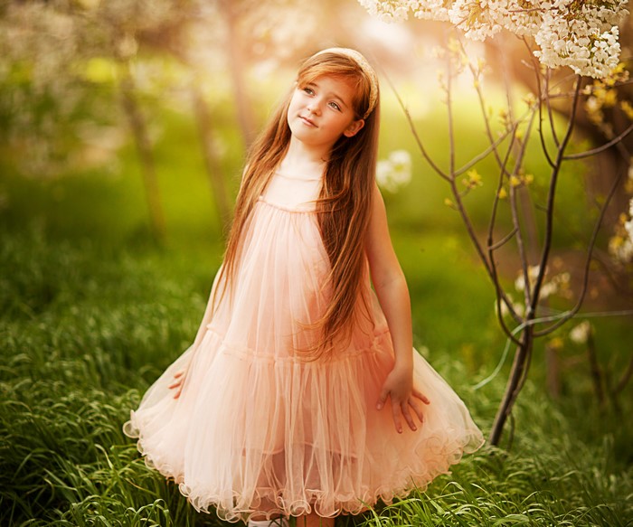 Young girl in a peach dress in a garden