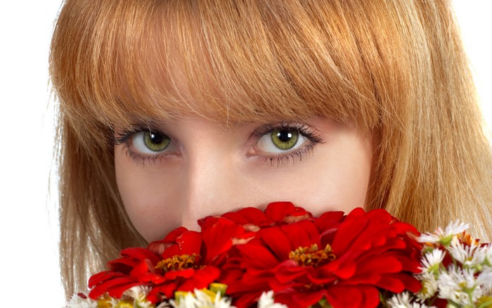 Blonde girl with green eyes holding red gerberas
