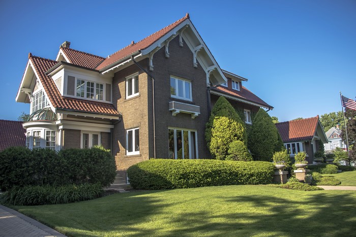 Brick house with red tile roof and manicured lawn