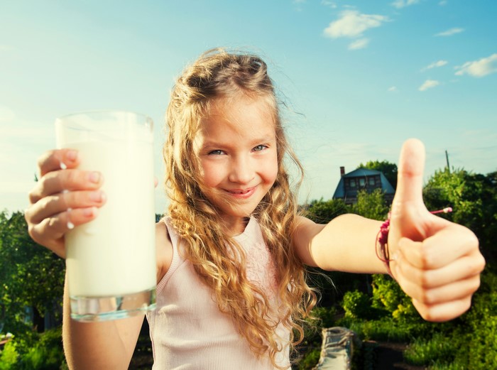 Girl holding milk glass with thumbs up