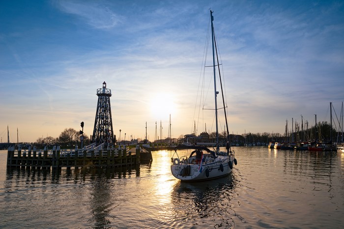 Sailboat and lighthouse in Enkhuizen harbor at sunset