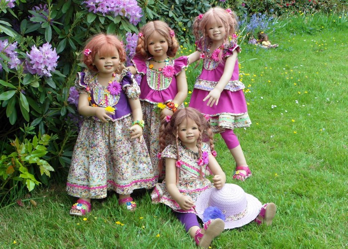 Four dolls in dresses in a garden