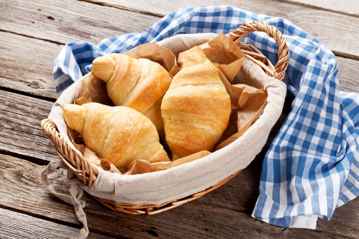 Croissants in a wicker basket with a blue checkered cloth