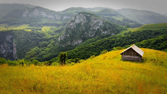 Wooden cabin in Romanian mountains with grasslands