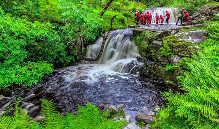 People in red suits at a waterfall in Wales