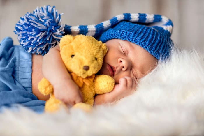Baby sleeping with teddy bear and winter hat