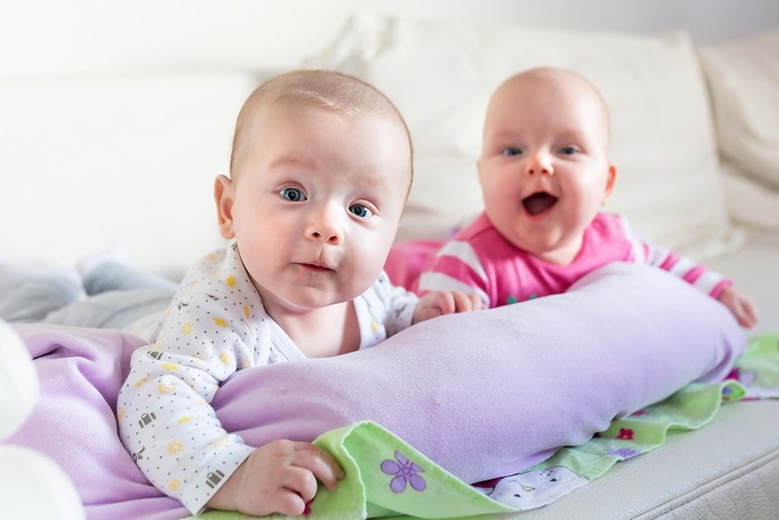 Two babies lying on a bed