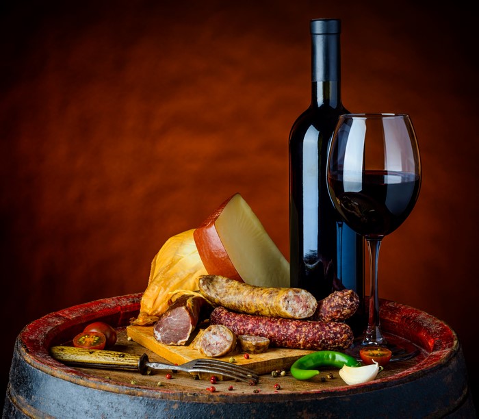 Still-life with wine, sausage, and cheese on a barrel