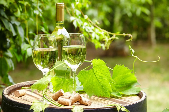 Two glasses of white wine and a bottle on a barrel