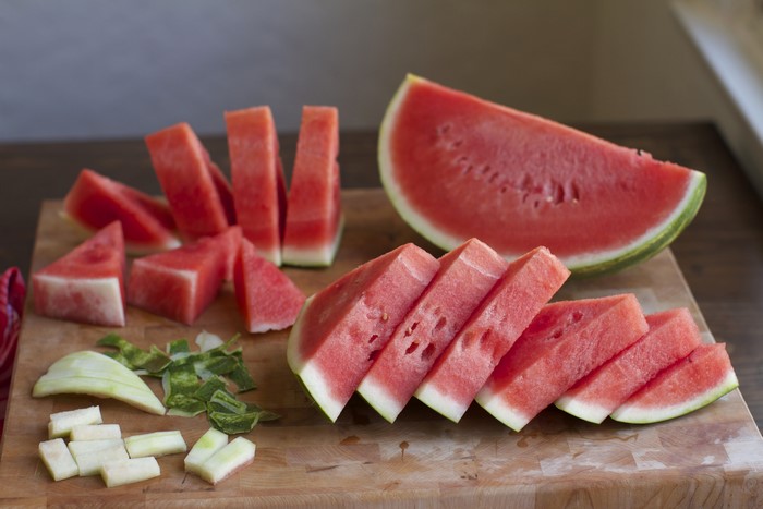 Watermelon slices and pieces on a cutting board