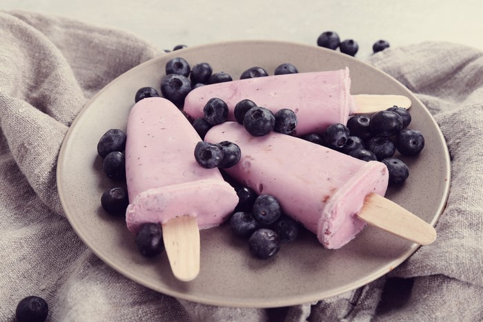 Blueberry ice pops on a plate with blueberries