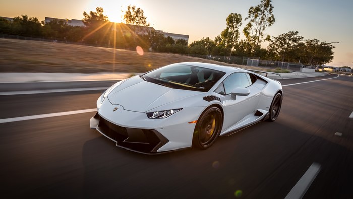 White Lamborghini Huracan driving on a road at sunset