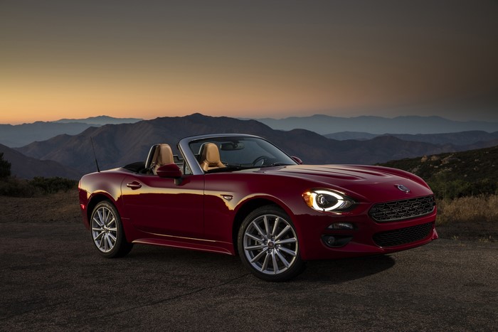 Red Fiat 124 Spider convertible on a mountain road