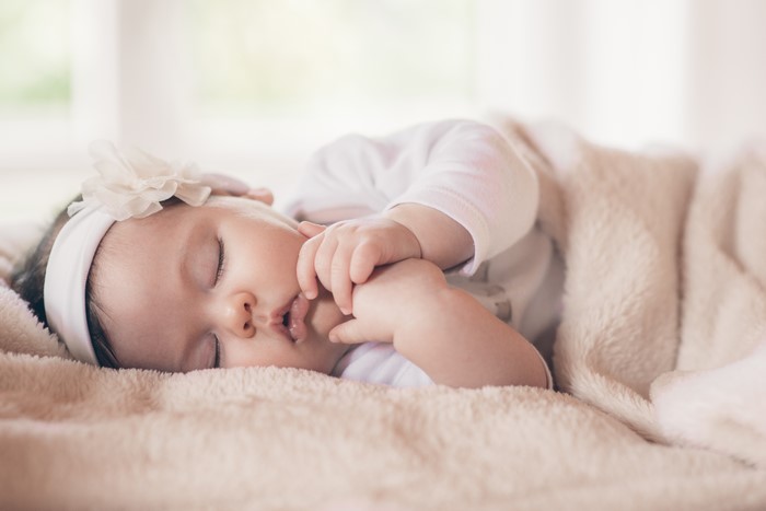 Infant sleeping on a blanket with a flower headband