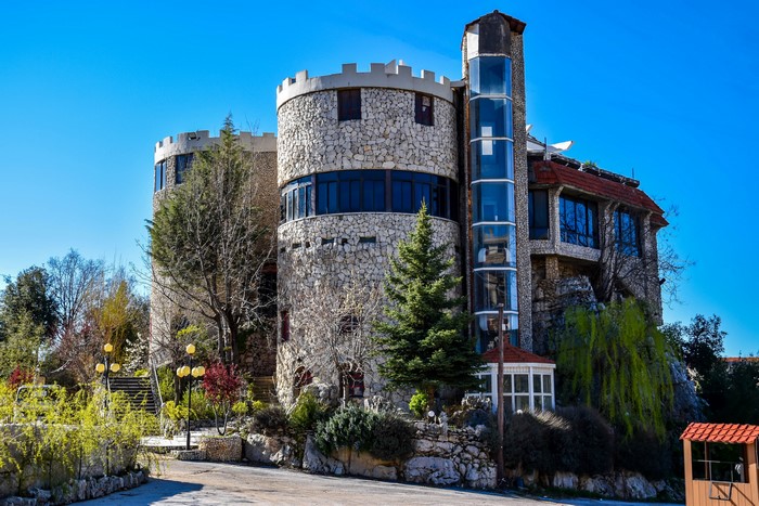 Castle-like building with stone towers and glass elevator in Al Barid, Lebanon