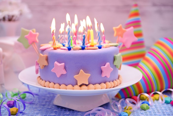 Birthday cake with lit candles and party hats