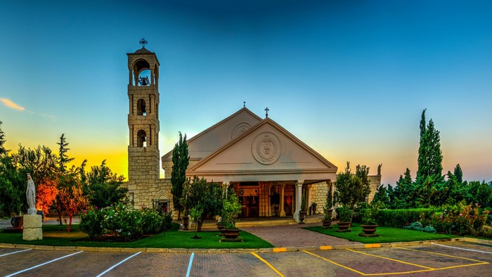 Church with bell tower and statue at sunset