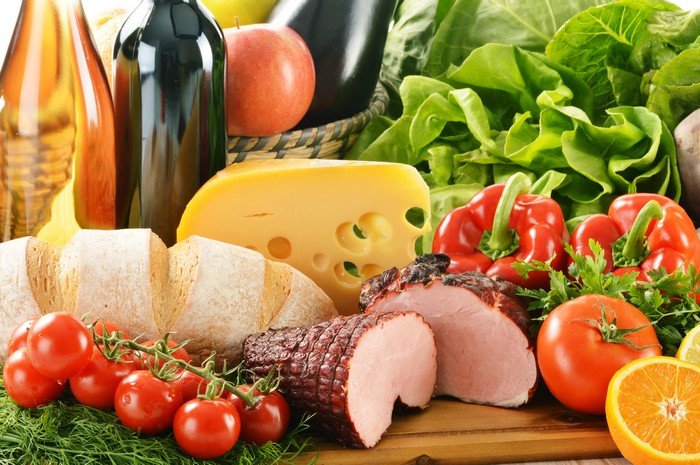 Still-life of cheese, ham, tomatoes, bread, and vegetables