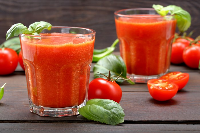 Two glasses of tomato juice with tomatoes and basil