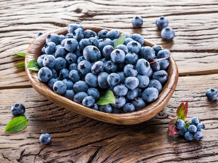 Blueberries in a wooden bowl on a wooden table