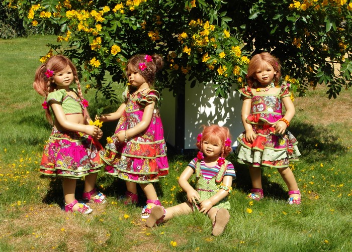 Four dolls in colorful dresses in a park