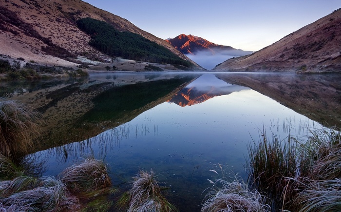 Mountain lake reflection at sunrise with mist