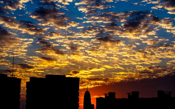 City skyline silhouette at sunset with dramatic clouds