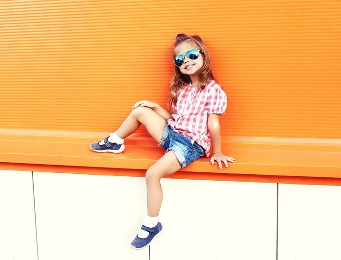 Girl in sunglasses sitting on an orange bench