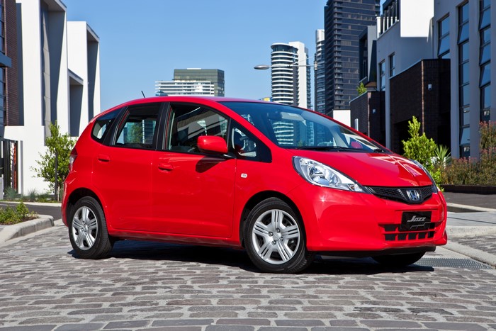 Red 2011-14 Honda Jazz parked on cobblestone street