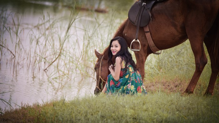 Asian woman with horse by the water