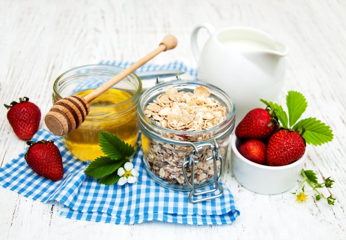 Still life of strawberries, honey, oats, and milk