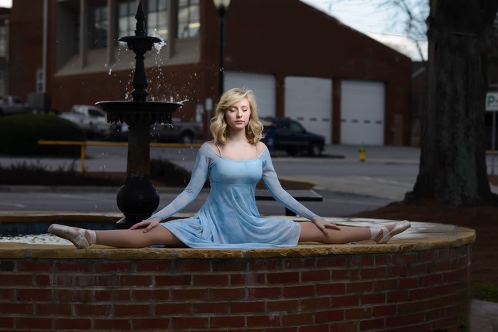 Blonde girl in blue dress doing a split