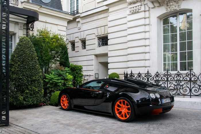 Black Bugatti Veyron with orange accents parked outside a building