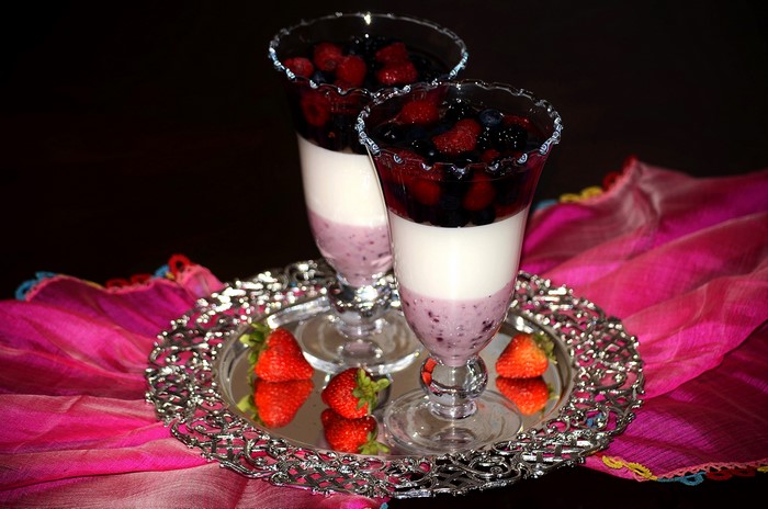 Two berry parfaits with strawberries on a silver tray