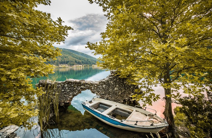 Boat by a lake with trees and ruins in Greece
