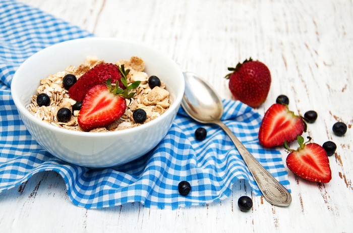 Bowl of muesli with strawberries and blueberries and a spoon