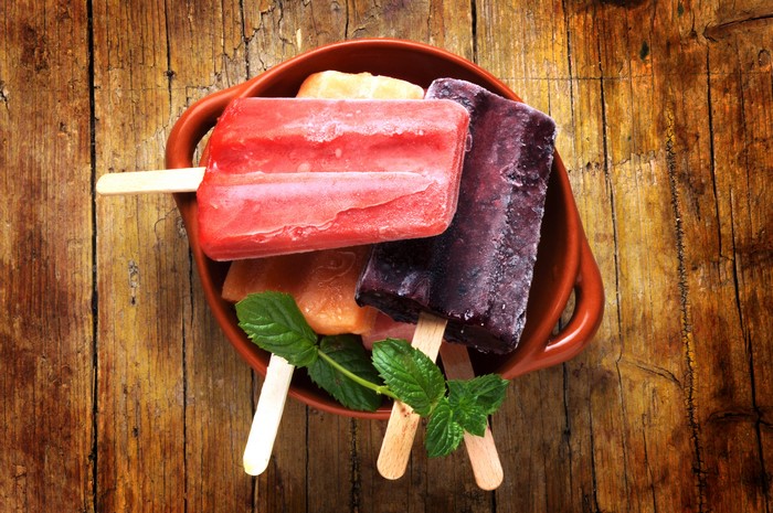 Assorted popsicles in a bowl on a wooden table