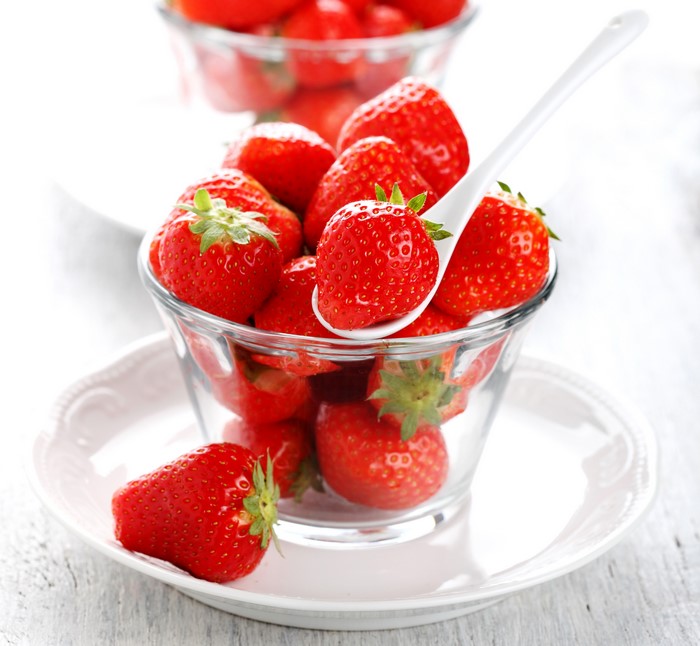 Strawberries in a glass bowl with a spoon