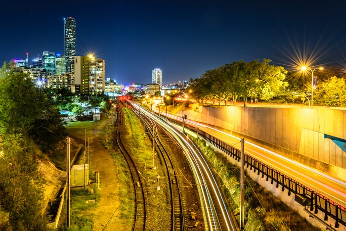 Brisbane city skyline at night with train tracks and highway