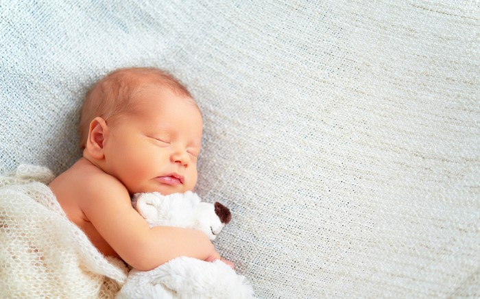 Newborn baby sleeping with a toy