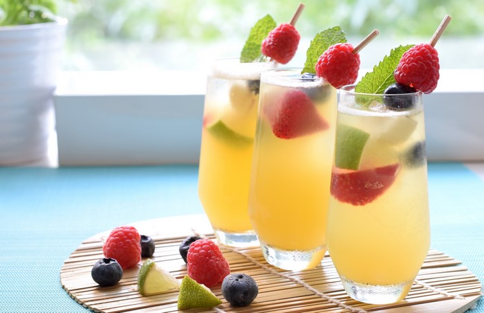 Three glasses of fruit infused drinks with berries and mint
