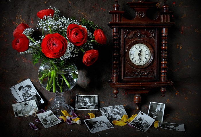 Still-life with red ranunculus, antique clock, and old photographs