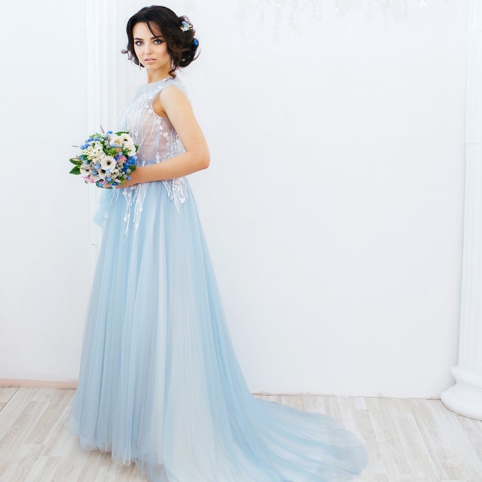 Brunette woman in a light blue dress holding a bouquet